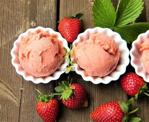 The image shows strawberry sorbet with strawberries and leaves.