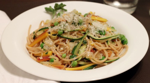The image shows a bowl of Pasta Primavera with colorful ingredients