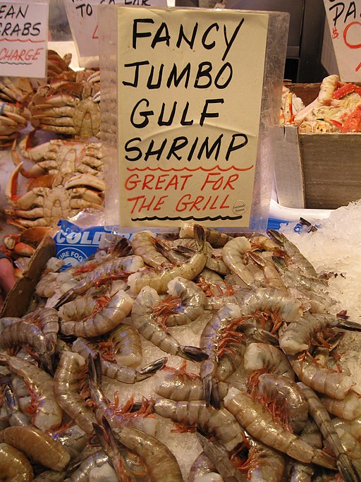 he image shows a pile of Gulf shrimp on a bed of ice at the seafood market.